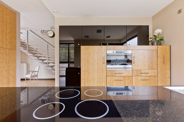 Kitchen interior with granite tabletop, wooden furniture and oven open to the staircase