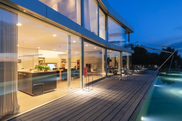 Switzerland, lighted modern villa at dusk with terrace and pool in the foreground